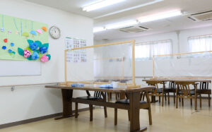 介護施設の活動・レクリエーションスペース。テーブルと椅子が配置された明るい室内。